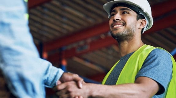 GIP team member smiling and shaking hands on a construction site