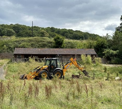 JCB excavator carrying out groundworks on rural contracting project.
