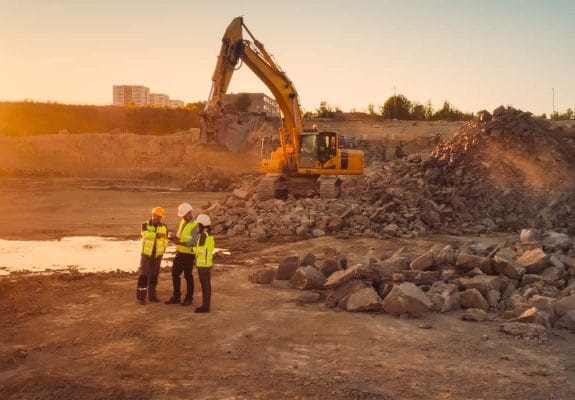 Engineers overseeing excavation work at a quarry site with excavators operating at sunset